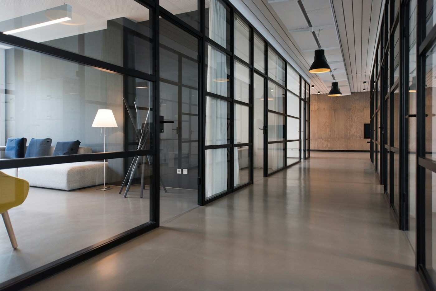 Glass-walled rooms and a sunlit corridor in a contemporary workspace
